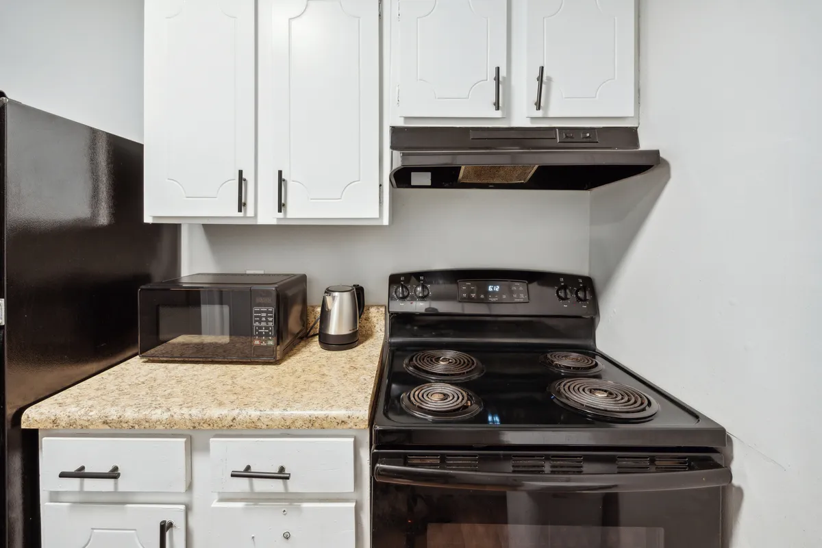 A close-up interior view of the kitchen, highlighting a modern stove, microwave, and kettle. The arrangement suggests readiness for everyday meal preparation as well as special occasions, with thoughtful placement and a cozy, inviting atmosphere.